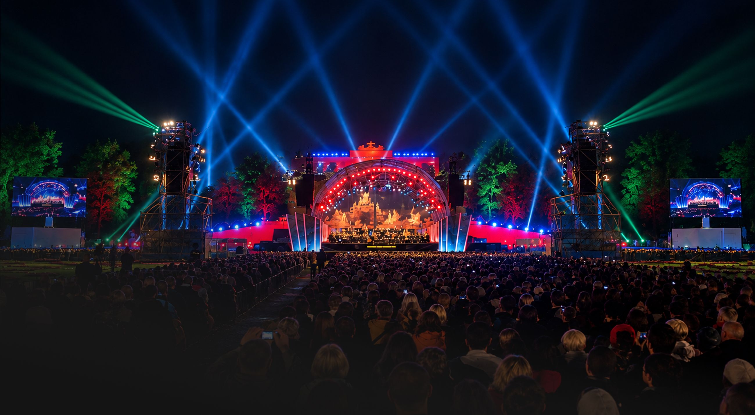 Große Open-Air-Bühne bei Nacht mit Publikum sowie roter, blauer und grüner Lichttechnik